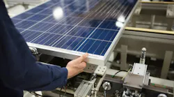 A production line worker helps assemble solar panels.